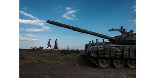Youngsters walk next to an abandoned tank belonging to Tigrayan forces south of the town of Mehoni, Ethiopia, in December 2020.