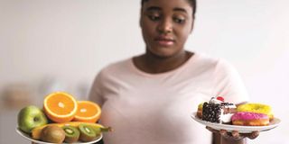 A woman holding plates with fruits and desserts.