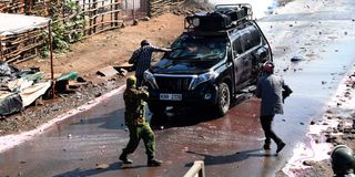 A man lobes a teargas canister into an empty vehicle that was part of the opposition leader Raila Odinga's entourage