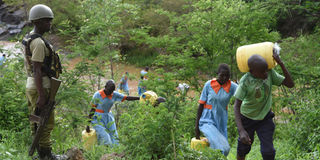 A policeman watches over pupils of Kapindasum Primary School in Baringo South Constituency, Baringo County as they fetch water