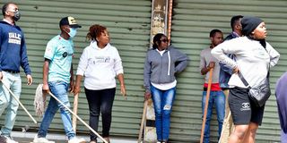 Various shop owners along Ronald Ngala Street on July 2, 2024 stand guard outside to secure their businesses premises